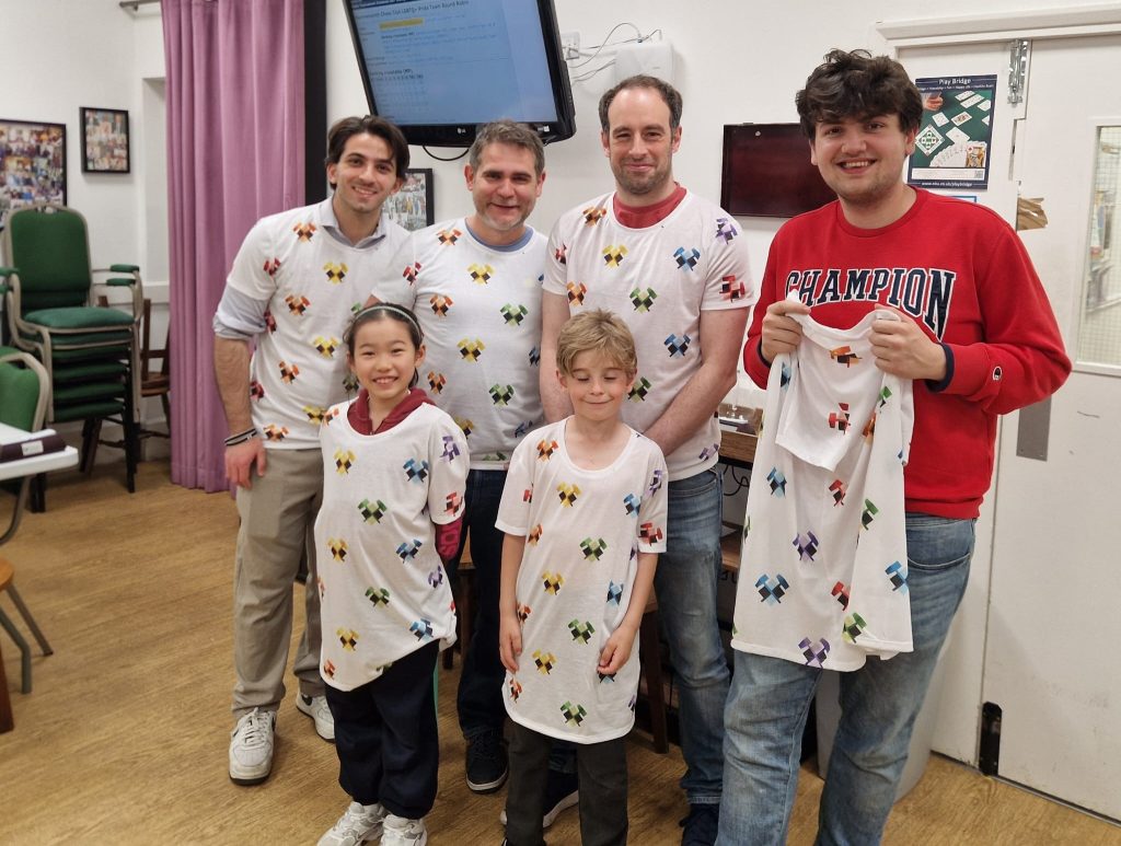 The smiling winning chess team of 4 adults and 2 children, wearing t-shirts decorated with the Hammersmith chess club logo of two crossed hammers, in rainbow colours.