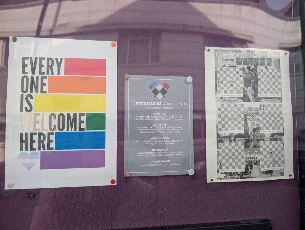 A poster up on the Hammersmith Chess Club noticeboard at then London Mindsports Centre. It has the colours of the rainbow flag plus a heart in the colours of the trans flag, and the text "everyone is welcome here".